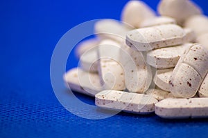 Many white medicine tablets on blue background. White pills, concept Ã¢â¬â pharmacy. Medicines drugs.